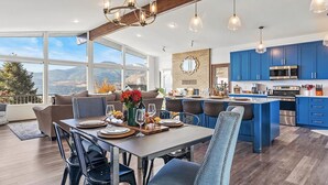Una cucina moderna con mobili blu, un'isola grande e un'area pranzo con vista sulle montagne.