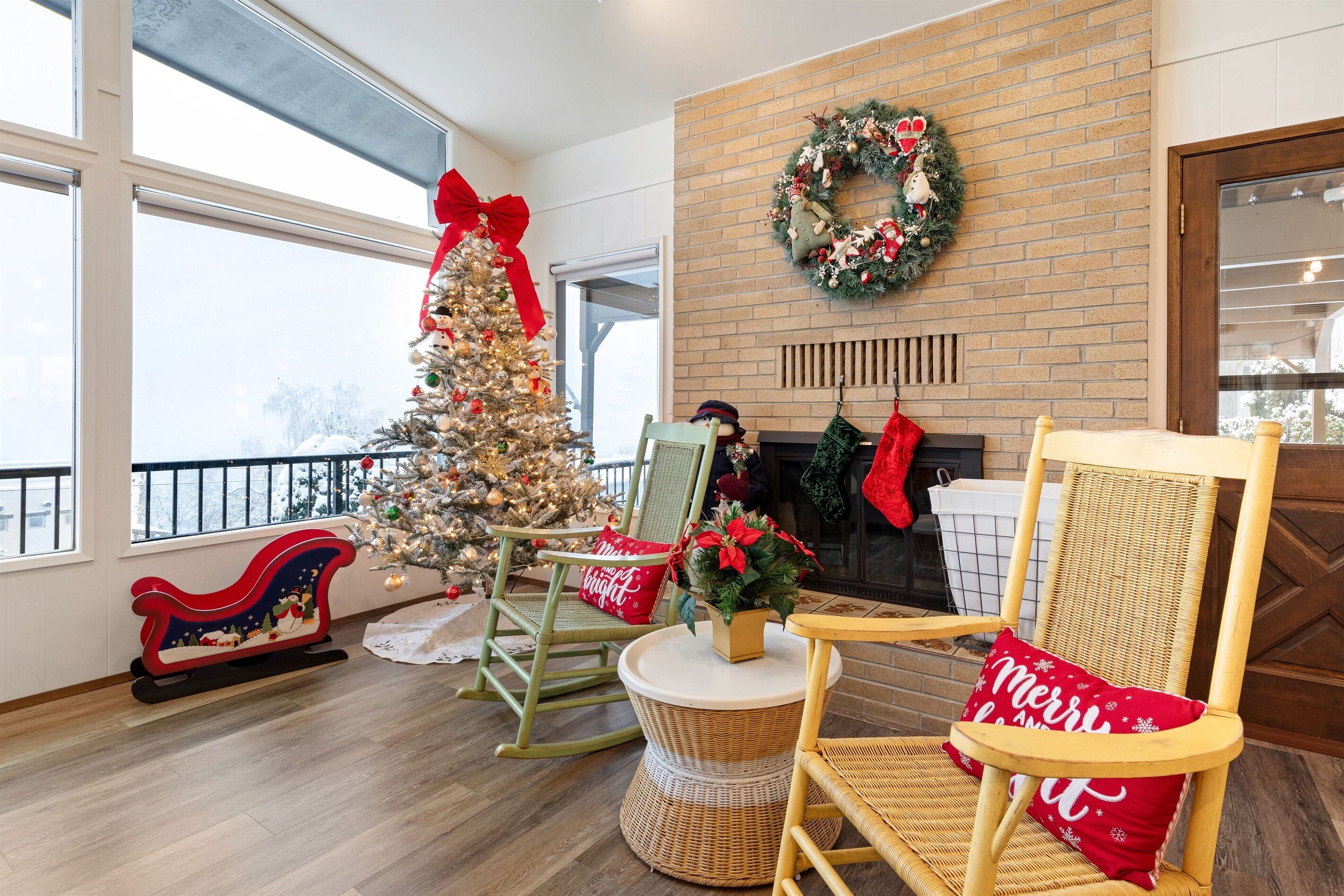 A cozy room with a brick fireplace, a Christmas tree, and wicker chairs.