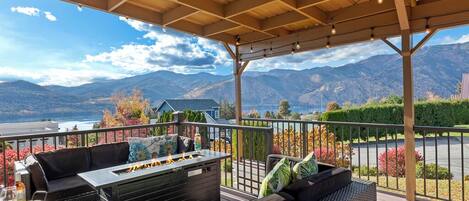 A covered outdoor seating area with a fire feature, overlooking a scenic mountain view.