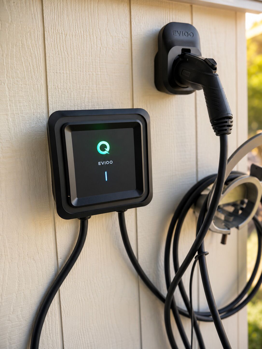Une borne de recharge dotée d’un écran numérique, d’un câble et d’une prise murale.