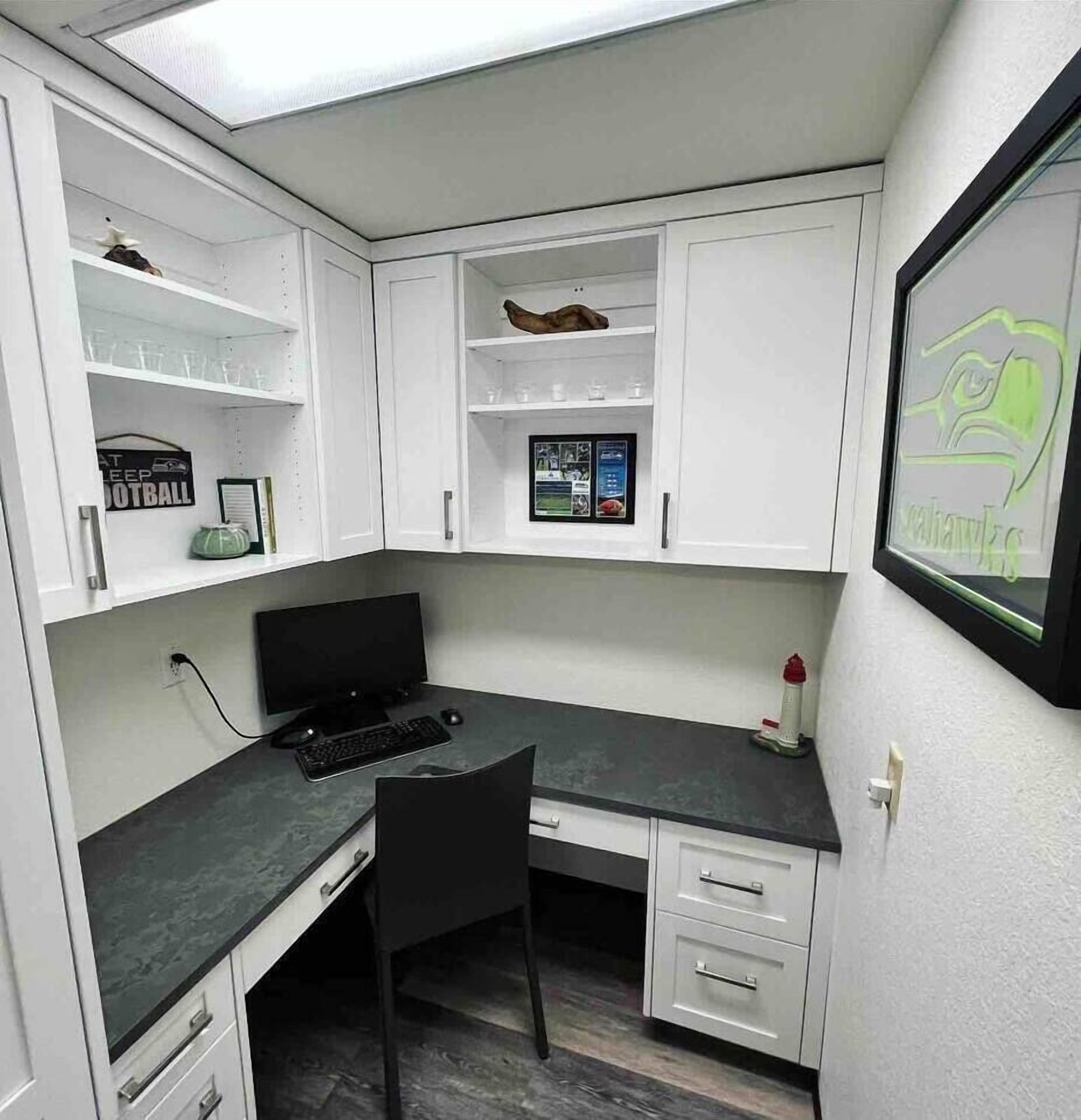 A compact office space with a desk, chair, and shelving units.