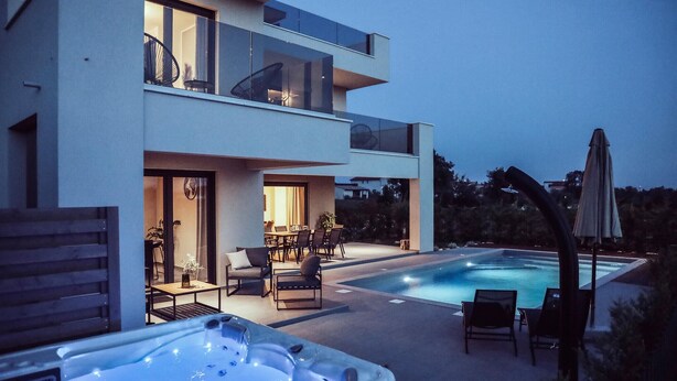 Una casa moderna de dos pisos con piscina y jacuzzi.