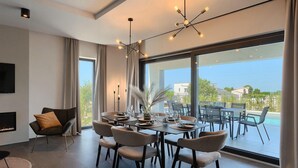 Un comedor moderno con un ventanal grande, chimenea y vistas a la piscina.