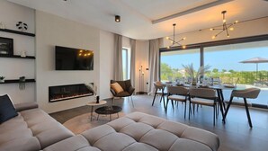Una sala de estar moderna con chimenea, un comedor con vistas y un ventanal grande.
