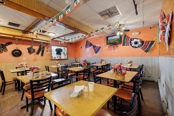 A restaurant interior with tables, chairs, and a television on the wall. - Cottage Suites (Middletown)