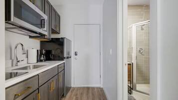 A compact kitchen with a modern design, including a stainless steel refrigerator, a built-in oven, and a coffee maker.