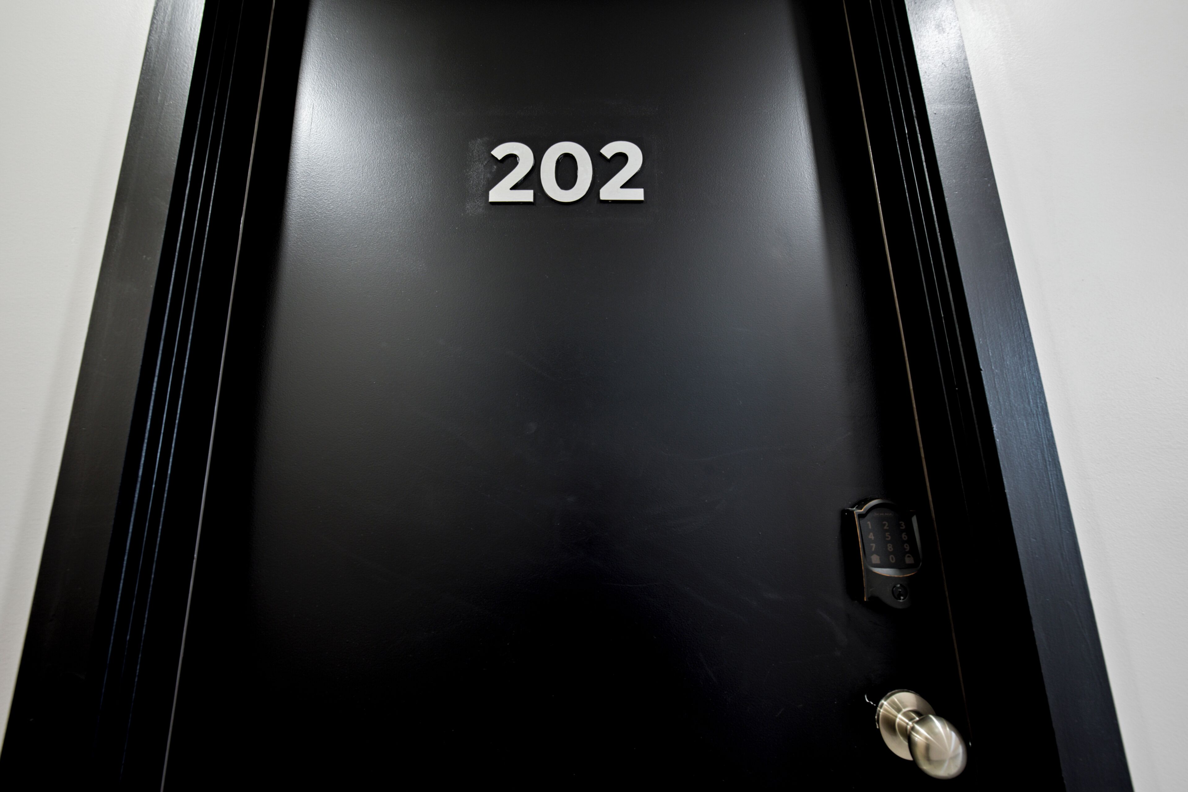 Una puerta negra con el número '202' y una cerradura.