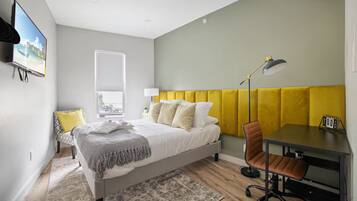 A bedroom with a bed, a desk, a chair, a lamp, and a window.
