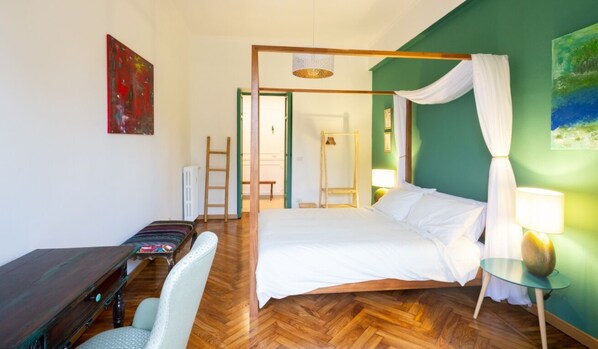 Une pièce comprenant un lit, un bureau, une chaise, une échelle et un tableau accroché au mur.