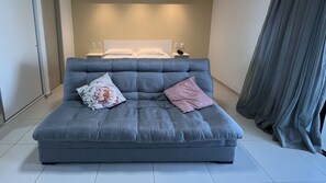 A grey sofa with floral and pink cushions in a hotel room. - Flat Frente Mar - Praia de Tabatinga (Conde)