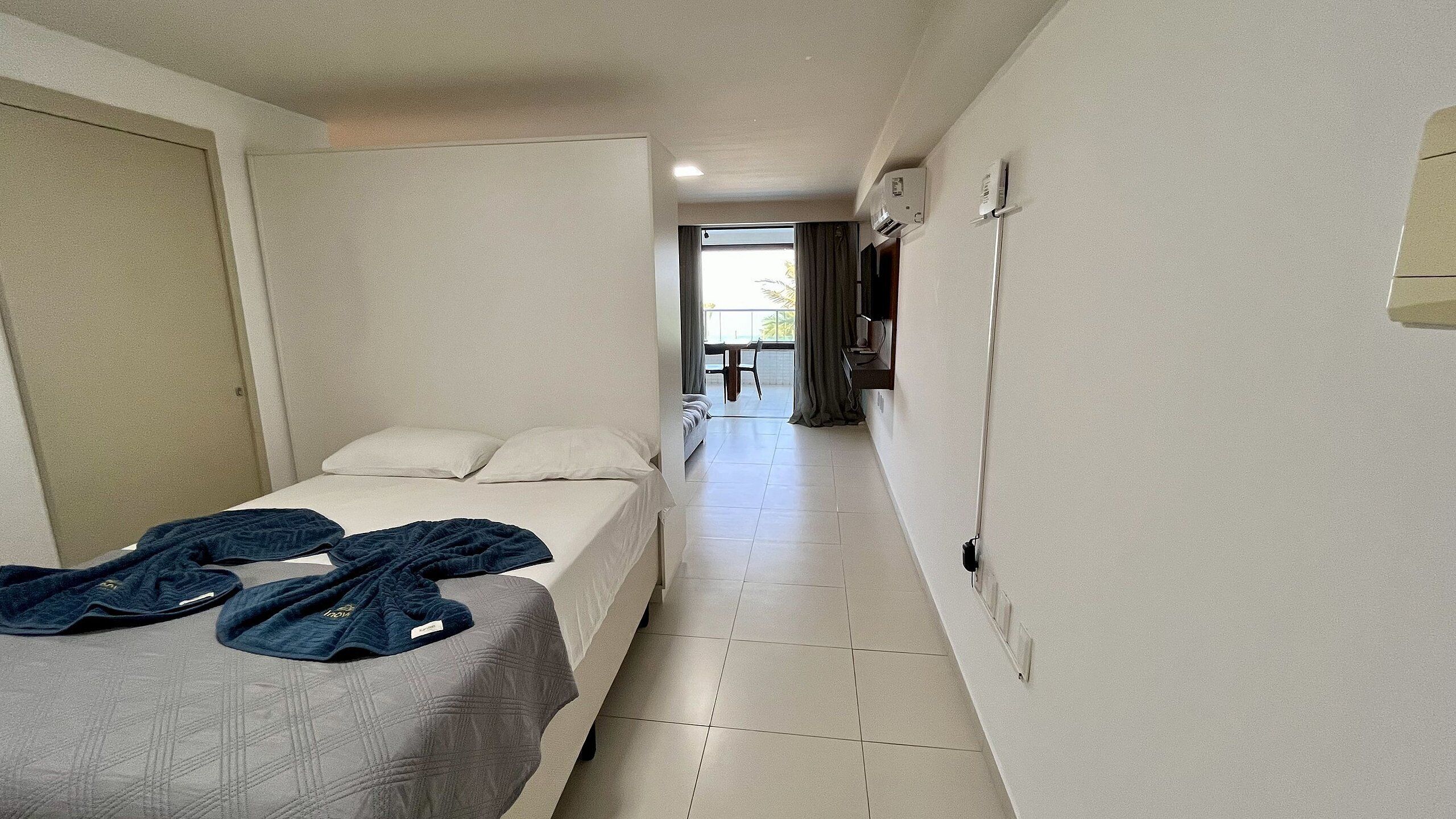 Una habitación de hotel con cama, una mesita y vistas al balcón.