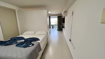 Una habitación de hotel con cama, una mesita y vistas al balcón.