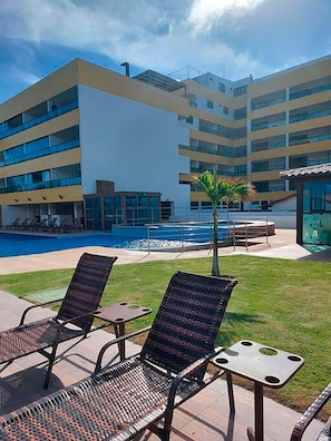 Zona de piscina amb gandules i una piscina, envoltada d'un edifici modern amb nombroses galeries.
