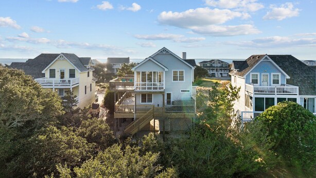 A coastal residential area with houses featuring balconies and decks, surrounded by dense greenery. - 5591- Beach, Please! - Soundside Escape in Nags Head | Dog Friendly (Nags Head)