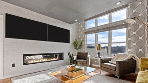 Un salon moderne doté d’une cheminée, de sièges confortables et de grandes fenêtres.