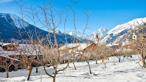 A snow-covered landscape with bare trees and a mountain backdrop.
