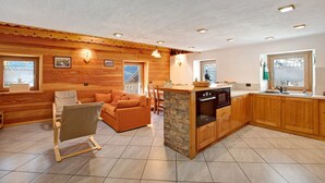A cozy cabin interior with a wooden interior, a stone island in the kitchen, and a view through the window.