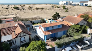 Zona residencial costera con casas de techo en tejas rojas, una playa de arena y una vista despejada del mar.