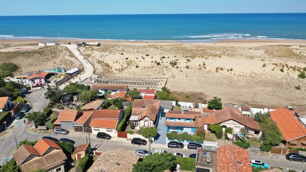 Un pueblo costero con una playa, casas con tejados rojos y una vista despejada del océano.