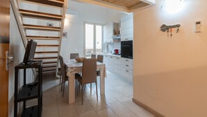 Una cocina con comedor, una escalera y un ventanal pequeño.