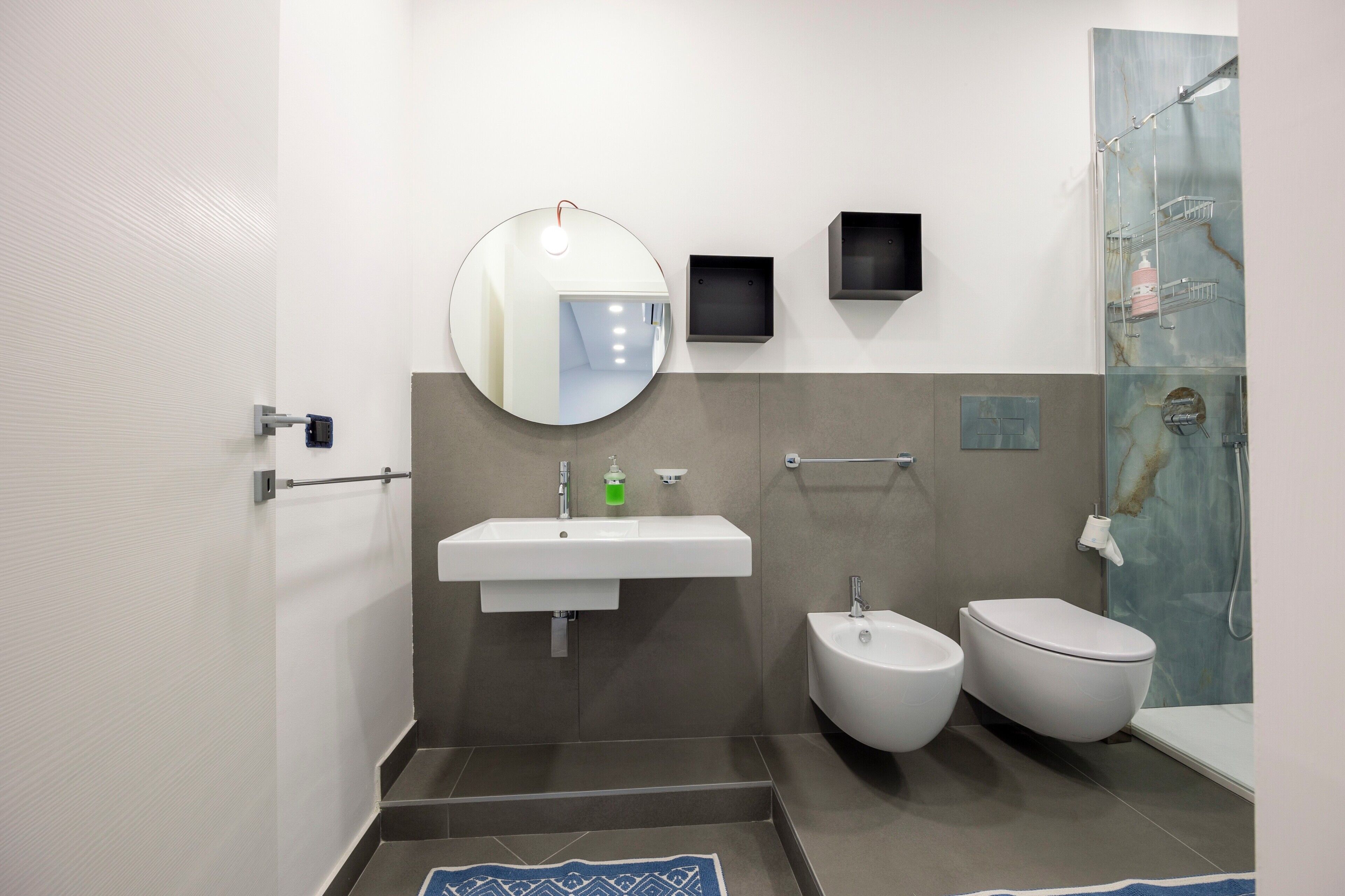 A modern bathroom with a sink, bidet, toilet, and a shower area.