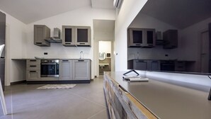 Een moderne keuken met inbouwapparatuur, een centraal eiland en een uitzicht op de aangrenzende badkamer.