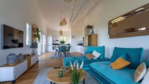 Un salon moderne avec un canapé de couleur turquoise, une table basse en bois et un grand miroir.