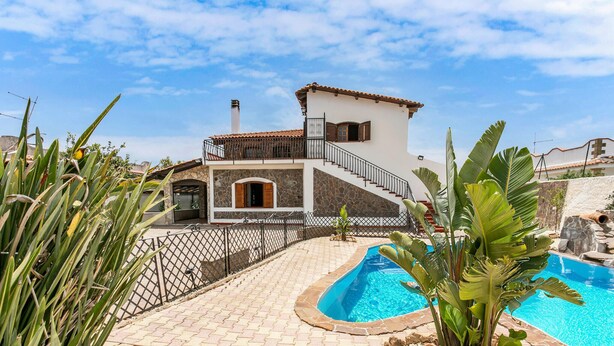 Une maison à deux étages avec une façade en pierre, une piscine et un escalier menant à l’étage supérieur.