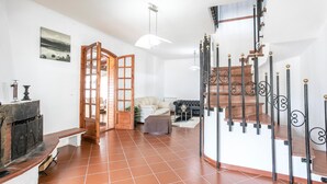 Un vaste espace de vie doté d’une cheminée, d’un canapé, d’une table basse et d’un escalier agrémenté de rampes décoratives.
