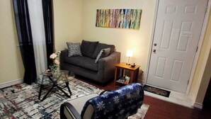 A living room with a sofa, a coffee table, a lamp, a patterned rug, and a door. - KASITA....5 min to river, 4min  to Christus S R hospital, state University 12min (San Marcos)