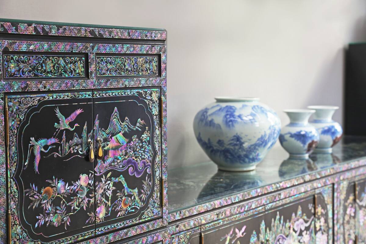 Un mueble decorativo con diseños intrincados y un jarrón encima.