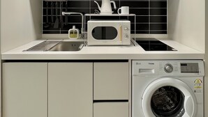 Una cocina compacta equipada con microondas, hervidor y lavadora.