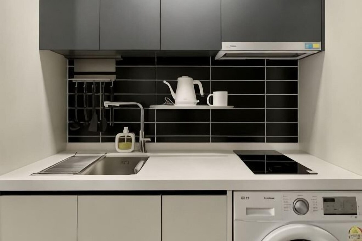 Une cuisine moderne équipée d’un évier, d’une cuisinière et d’un lave-linge.