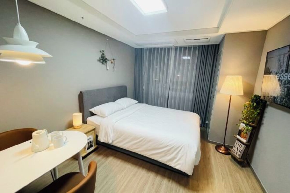 Una habitación de hotel moderna con cama, mesita de noche y escritorio con sillas.