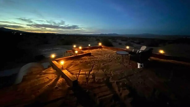 Un espace extérieur aménagé avec des sièges, offrant une vue sur le paysage désertique au crépuscule.