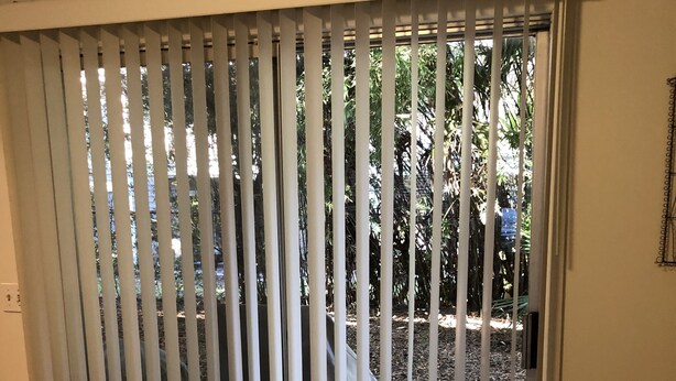 Una habitación con una silla blanca, un felpudo marrón y un letrero sobre una puerta corredera de vidrio.