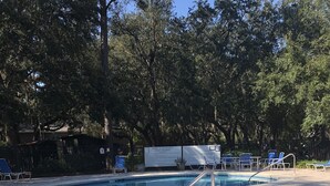 Una piscina con sillas reclinables azules y un cartel.