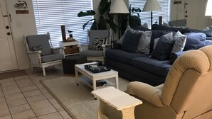 Una sala de estar con un sofá, dos sillones, una mesa baja y una mesita auxiliar.