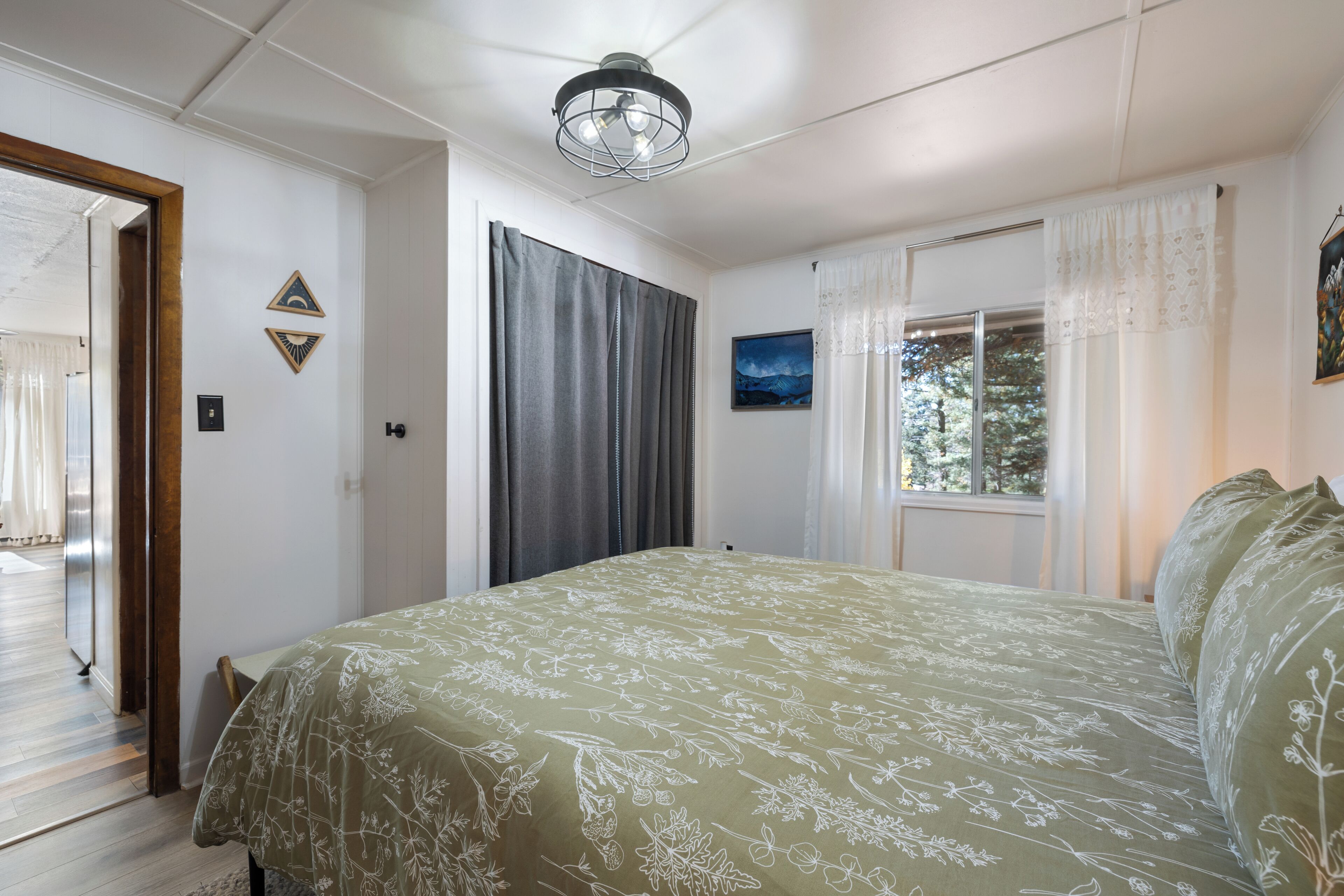 A bedroom with a bed, a door, a window, and a ceiling light.