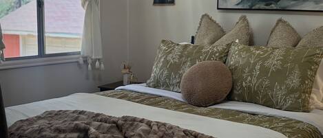 Una cama bien hecha con almohadas estampadas, un edredón mullido y un cuadro en la pared.