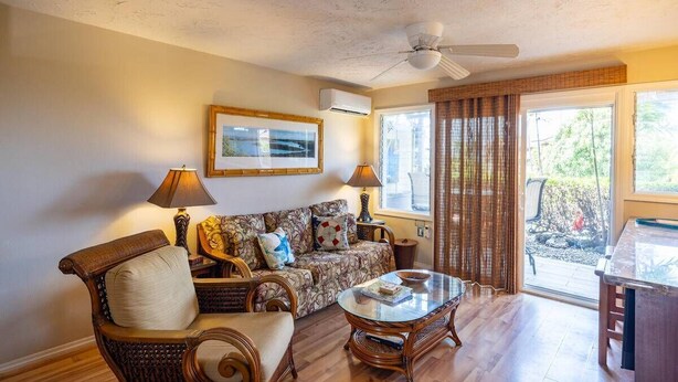 A living room with a sofa, two chairs, a coffee table, a ceiling fan, and a window with curtains. - Peek-a-boo Ocean View,1bd1bath AC Condo, closer to downtown Kailua village (Kailua-Kona)