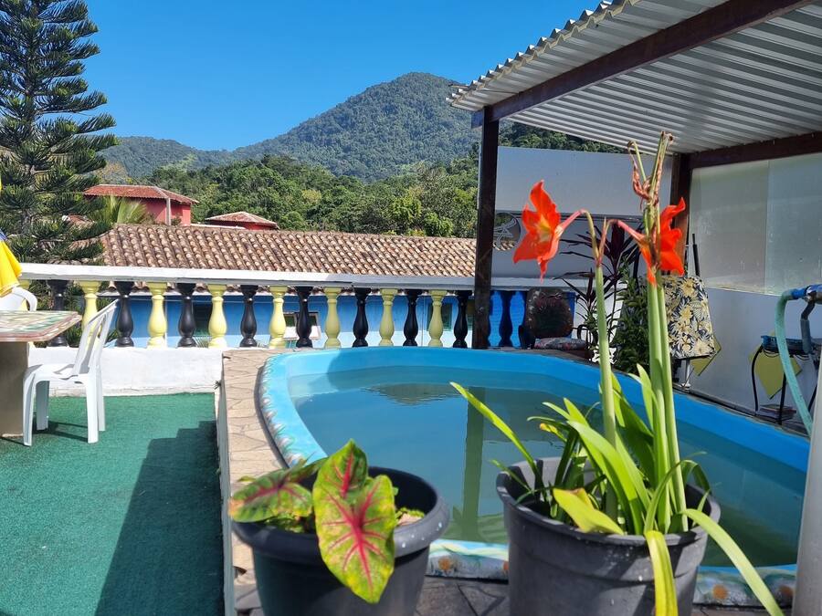 Zona de piscina con plantas en macetas, un suelo de baldosas y vistas a una montaña.