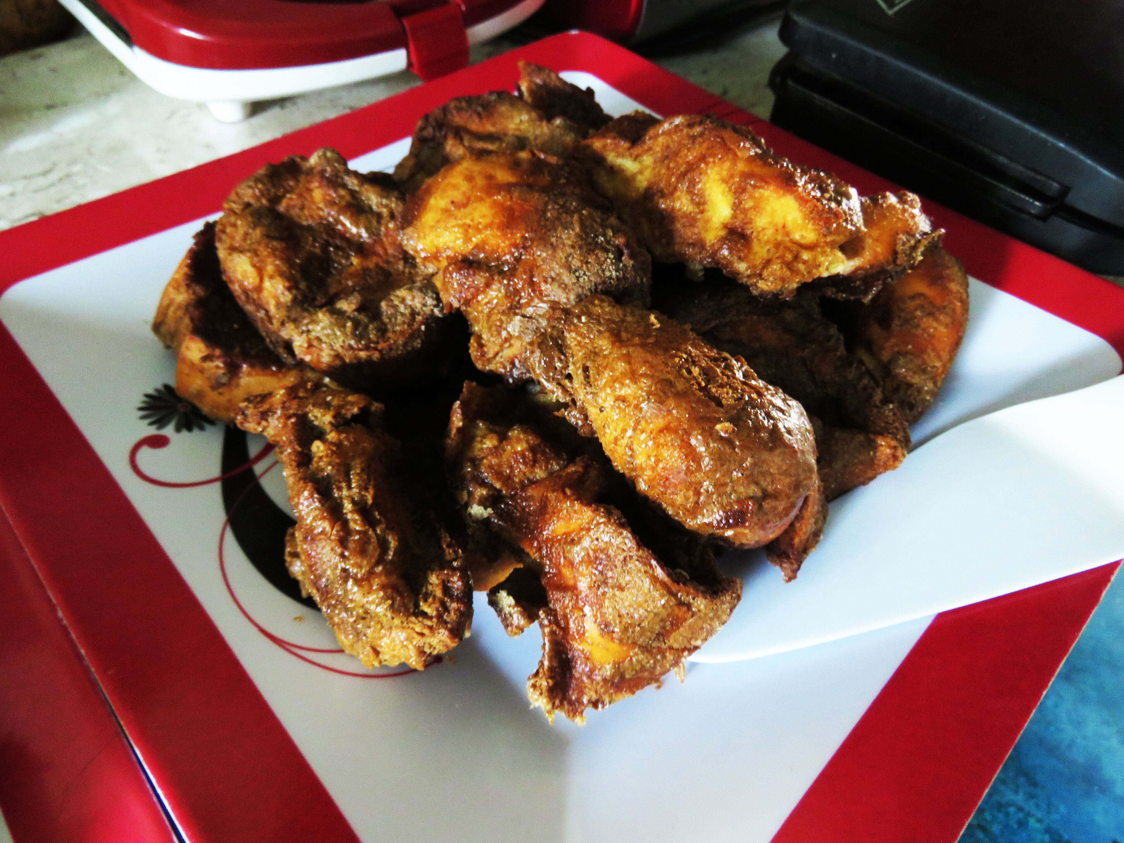 Une assiette de poulet frit sur une table blanche et rouge.