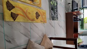 Un dormitorio con cama, mesita de noche de madera, televisor y obra de arte en la pared.