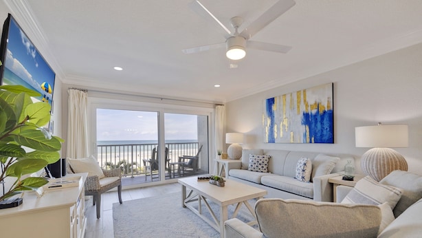 Un salon moderne avec un balcon, des meubles blancs et un grand tableau abstrait.