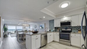 Une cuisine moderne avec des meubles blancs, des appareils en acier inoxydable et un îlot central.