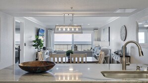 Une cuisine moderne dotée d’un grand îlot central, d’un coin repas offrant une vue agréable et d’un espace de vie avec balcon.
