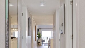 Un couloir doté d’un sol carrelé de couleur claire, de murs blancs et d’une porte située sur le côté droit.