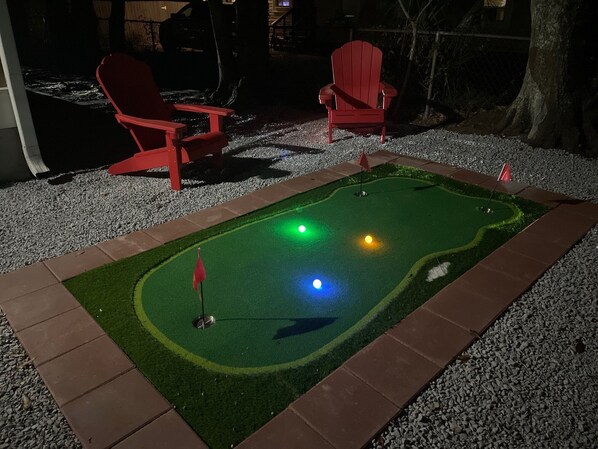 Un campo de mini golf con dos sillas rojas y un área de práctica de putt.