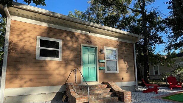 A single-story house with a green door, a small front porch with steps, and a gravel driveway. - Peachy Beach House - Unit A - Close to beach, game Room, Putting Green, & more! (Gulfport)